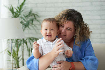 Portrait of happy loving plus sive woman hugging her adorable mixed-race baby boy