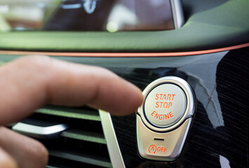 Engine Start Stop Button with blurred finger pressing the button on background. Car Start stop button on keyless technology.
