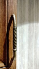Fototapeta na wymiar a bronze twisted curly handle is screwed onto the wooden door
