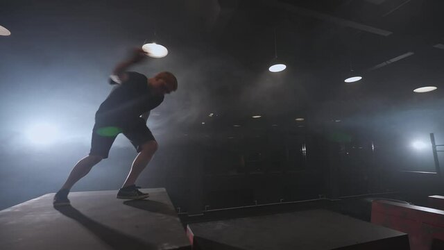 Free running, young man doing a series of somersaults on the training ground for parkour and workout, guy perform flips and gymnastic tricks in a dark space, 4k slow motion.