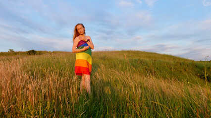 Bisexual, lesbian, woman, person, homosexual naked with LGBT flag on the green hills on a sunny day sunset and celebrating a gay parade, Bisexuality Day or National Coming Out Day in pride month