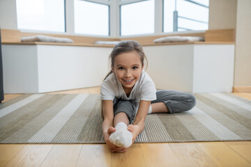 Naklejka premium Cute girl sitting on the floor and stretching