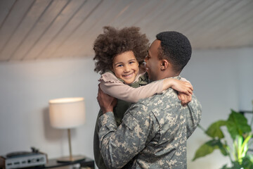 Happy little girl in arms of military man - obrazy, fototapety, plakaty