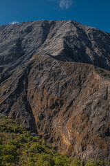 vertical shot with green vegetation and canyon with brown rocky elevation of volcanic origin formed by ancient lava flows in a sunny day Los Quemaderos del Poás Volcano National Park