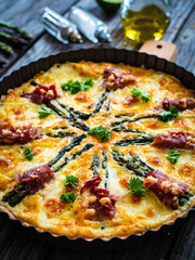 Tart with asparagus and serrano ham on wooden table
