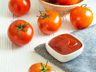 Tomato sauce in gray bowl and tomatos on white wooden table, Copy space for word. Homemade food.