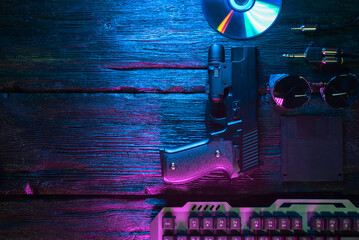 Cyberpunk concept. Cybersport. Guns and computer keyboard in the neon lights on the black flat lay...