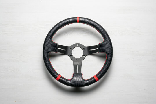 A sport car steering wheel on the white flat lay background.
