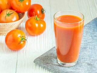 Fresh tomato juice in glass and tomatos on white wooden table, Copy space for word. Healthy drink in morning concept.