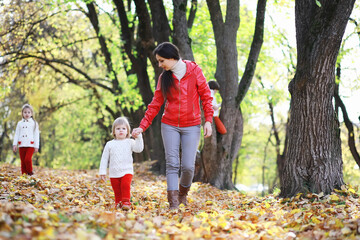 Naklejka premium Children for a walk in the autumn park. Leaf fall in the park. Family. Fall. Happiness.