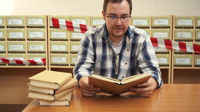 A man reads a book in the library sitting at the table