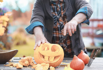 Autumn traditions and preparations for the holiday Halloween. A house in nature, a lamp made of pumpkins is cutting out at the table.