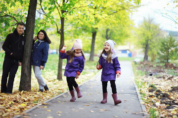 Fototapeta premium Leaf fall in the park. Children for a walk in the autumn park. Family. Fall. Happiness.