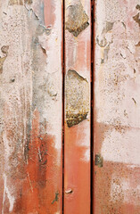 very old metal plates of red color with a crossbar with peeling paint covered with rust