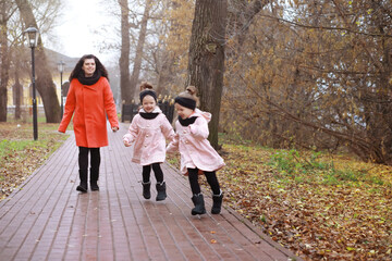 Young family on a walk in the autumn park on a sunny day. Happiness to be together.