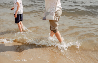 Mother and child walking on a sandy beach. Cool water in the sea. Walk along the beach barefoot....