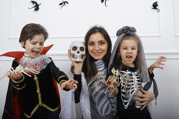 Happy family with children in costumes of witch and vampire in a house in holiday Halloween