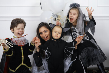 Happy family with children in costumes of witch and vampire in a house in holiday Halloween - obrazy, fototapety, plakaty