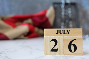 Cube wooden calendar showing date on 26 July. Wooden calendar with date on the table. blur objects on background