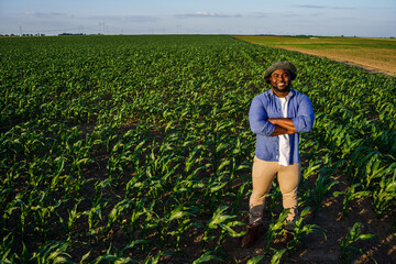 Farmer is standing in his growing corn field. He is satisfied after successful sowing.