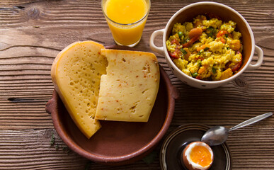 Boiled rice and vegetables with matured cheese, boiled egg and orange juice on wooden background
