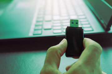 Hacker cyber holding usb flash drive for save data from laptop computer with green over light....