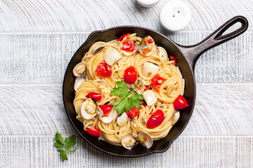 Spaghetti alle vongole or with clams, tomato and parsley, italian pasta with seafood. Light wood background.