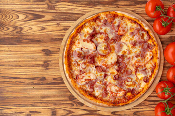 Top view of freshly baked pizza on wooden background
