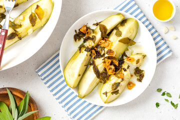 Stewed zucchini with herbs and garlic in a white plate on a gray concrete background. Summer recipes, vegan food, diet.