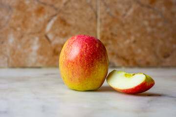 Close up of an apple with a slice on a marble background.