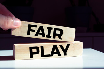 The words FAIR and PLAY are written on wooden blocks in black letters