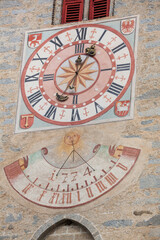 Fototapeta na wymiar The recently restored clock and sundial painted outside the bell tower of the church of the town.