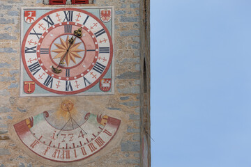 Obraz premium The recently restored clock and sundial painted outside the bell tower of the church of the town.