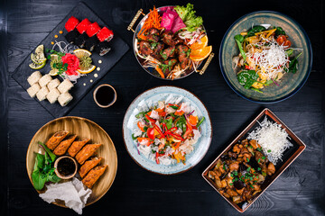 Asian food cooking. Wok, noodles and vegetables salad and chopsticks on dark rustic background