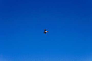 Naklejka na ściany i meble Old plane flies alone in blue sky airplane