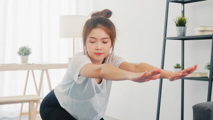 Young Korean lady in sportswear exercises doing working out and using laptop to watching yoga video tutorial at home. Distant training with personal trainer, social distance, online education concept.
