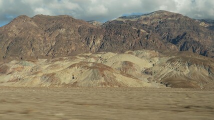 Road trip to Death Valley, Artists Palette drive, California USA. Hitchhiking auto traveling in America. Highway, colorful bare mountains and arid climate wilderness. View from car. Journey to Nevada.