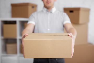 Close up of man giving a box in warehouse or post office.