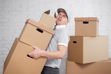 Tired deliveryman holding many boxes in hands.