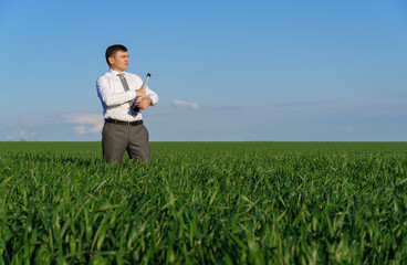 businessman poses with a spyglass, he looks into the distance and looks for something, green grass and blue sky as background