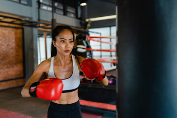 Young Asia lady kickboxing exercise workout punching bag tough female fighter practice boxing in gym fitness class. Sportswoman recreational activity, functional training, healthy lifestyle concept. - obrazy, fototapety, plakaty
