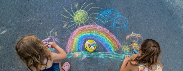 Children paint a rainbow on the asphalt. Selective focus.