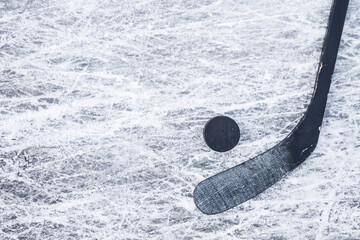 Black hockey stick and rubber puck on ice background. Closeup. Empty place for text. Top down view.
