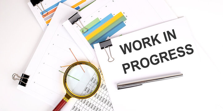 Work In Progress text on white paper on a light background with charts paper