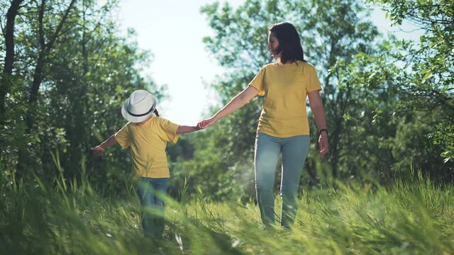 Happy family. Mom and daughter in forest park. People walk on grass. Happy team mom and daughter. Family is walk on grass in park. People walk along the tava in forest. Happy family concept