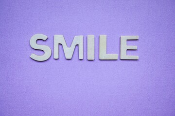 smile word with wooden letters on the purple background