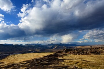 mountain panorama, ancient lava flow, and ominous clouds on a sunny day along the  north table mountain trail in golden. colorado