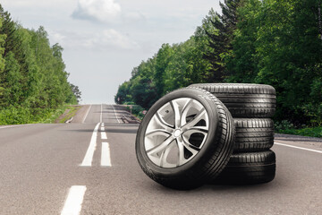 summer tires and alloy wheels set on an asphalt road. tire change season, auto trade, copy space ,...