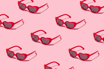 Creative pattern made with red heart shaped sunglasses on pastel pink background. Summer sunny...
