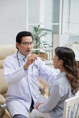 Obraz premium Doctor asking senior patient to open mouth so he could check her throat